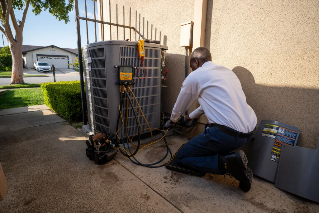 A Swan Plumbing, Heating, and Air technician performing outdoor condenser maintenance during triple-play check